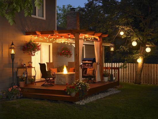 A patio with a fire pit under a pergola at night