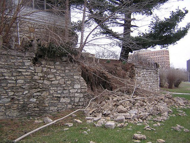A large pile of rocks is sitting in front of a stone wall