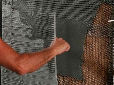 A man is using a trowel to spread cement on a wall.