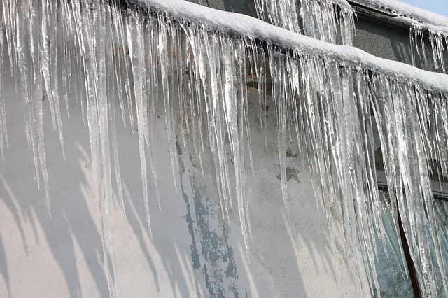 Icicles are hanging from the roof of a building.