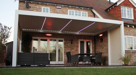 A house with a patio with a table and chairs under a pergola.
