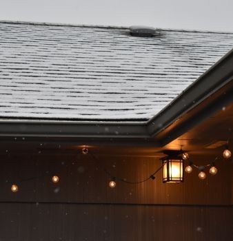 A roof with snow on it and a string of lights hanging from it
