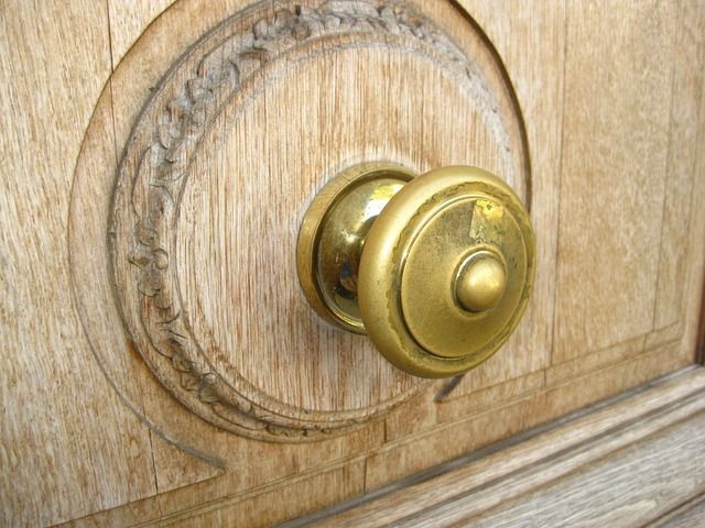 A close up of a brass door knob on a wooden door.