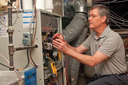 A man is working on an air conditioner in a basement.