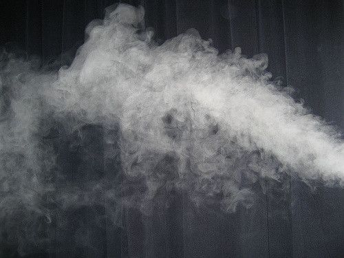 A close up of smoke coming out of a machine on a black background.
