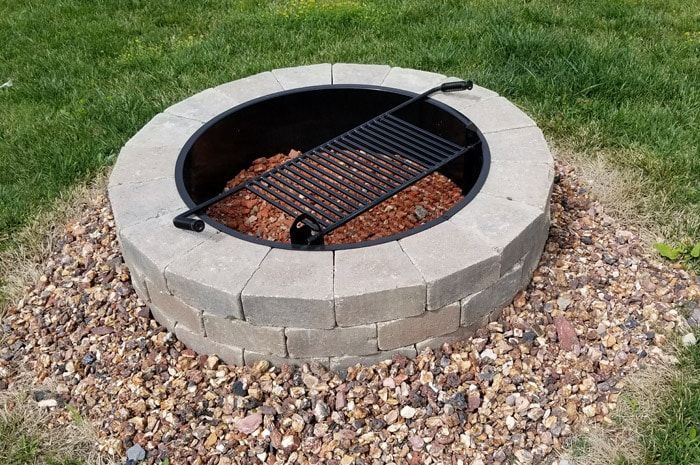A fire pit with a grill in the middle of it.