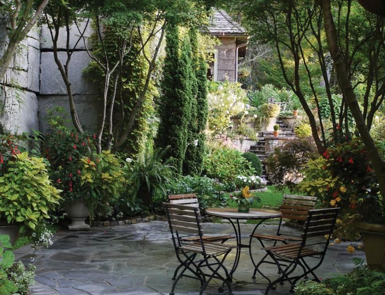 A patio with a table and chairs in a garden