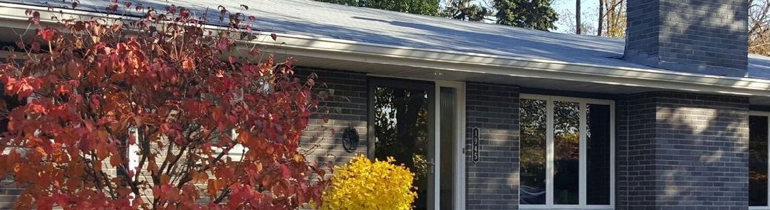 A brick house with a chimney and a tree in front of it.