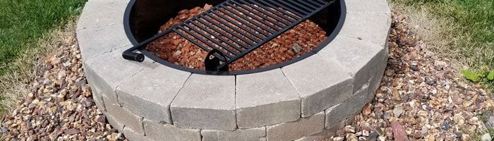 A fire pit with a grill in the middle of it.