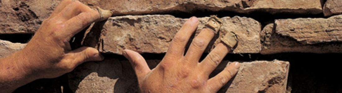 A person is putting their hands on a brick wall.
