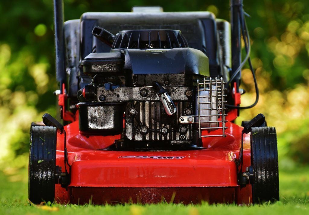 A red lawn mower is sitting on top of a lush green lawn.