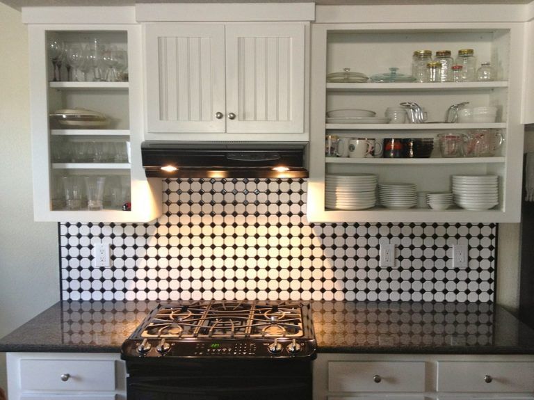 A kitchen with black and white tiles and a stove top oven