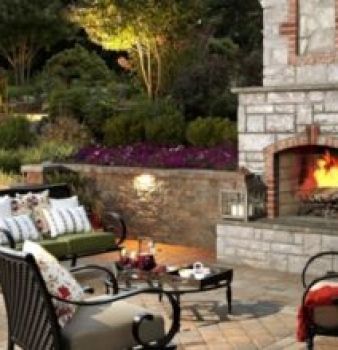 A patio with a fireplace and a couch and chairs