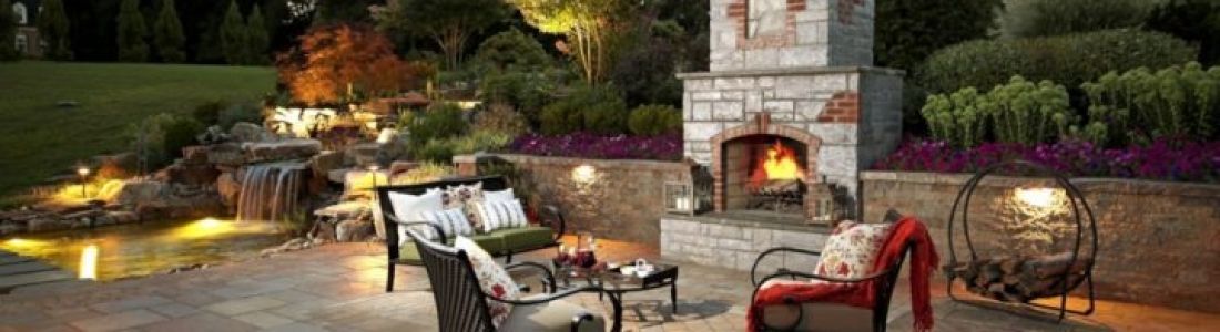 A patio with a fireplace and a waterfall in the background.
