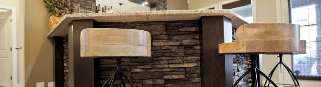 A kitchen with a bar and stools in front of a stone fireplace.