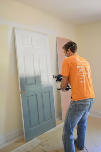 A man in an orange shirt is painting a door