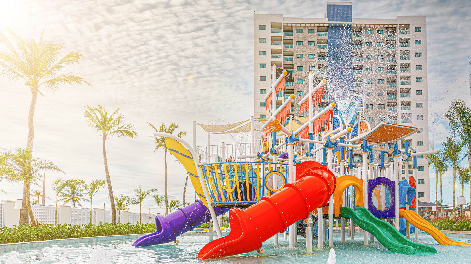 Um parque aquático com toboáguas e uma fonte em frente a um prédio.