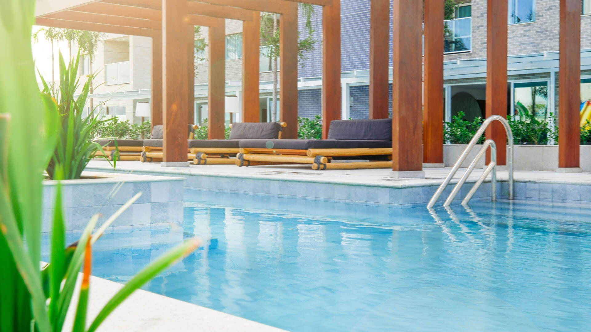 Uma grande piscina com uma pérgola de madeira e escadas que levam até ela.
