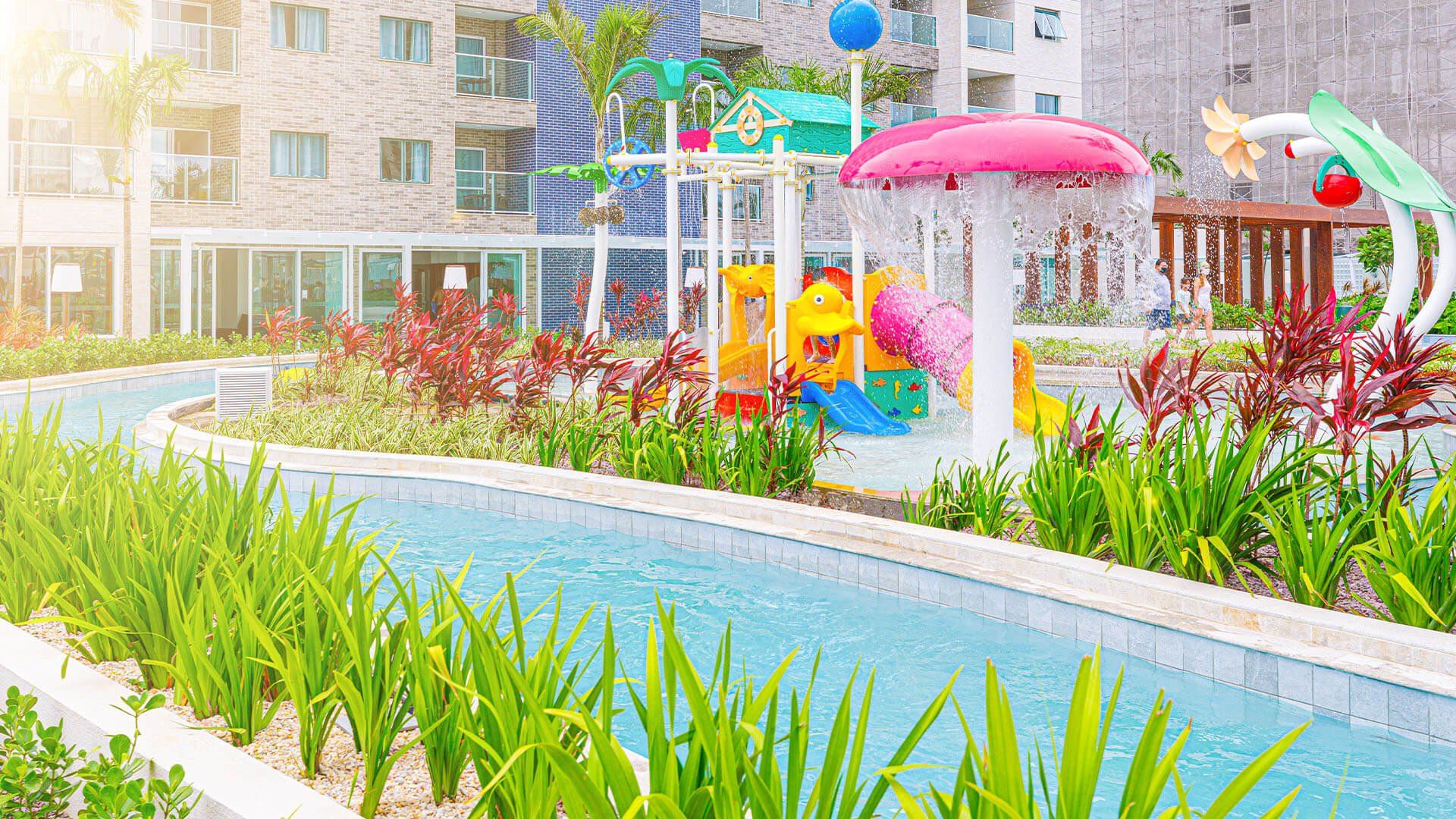 Uma piscina com toboágua e um playground ao fundo.