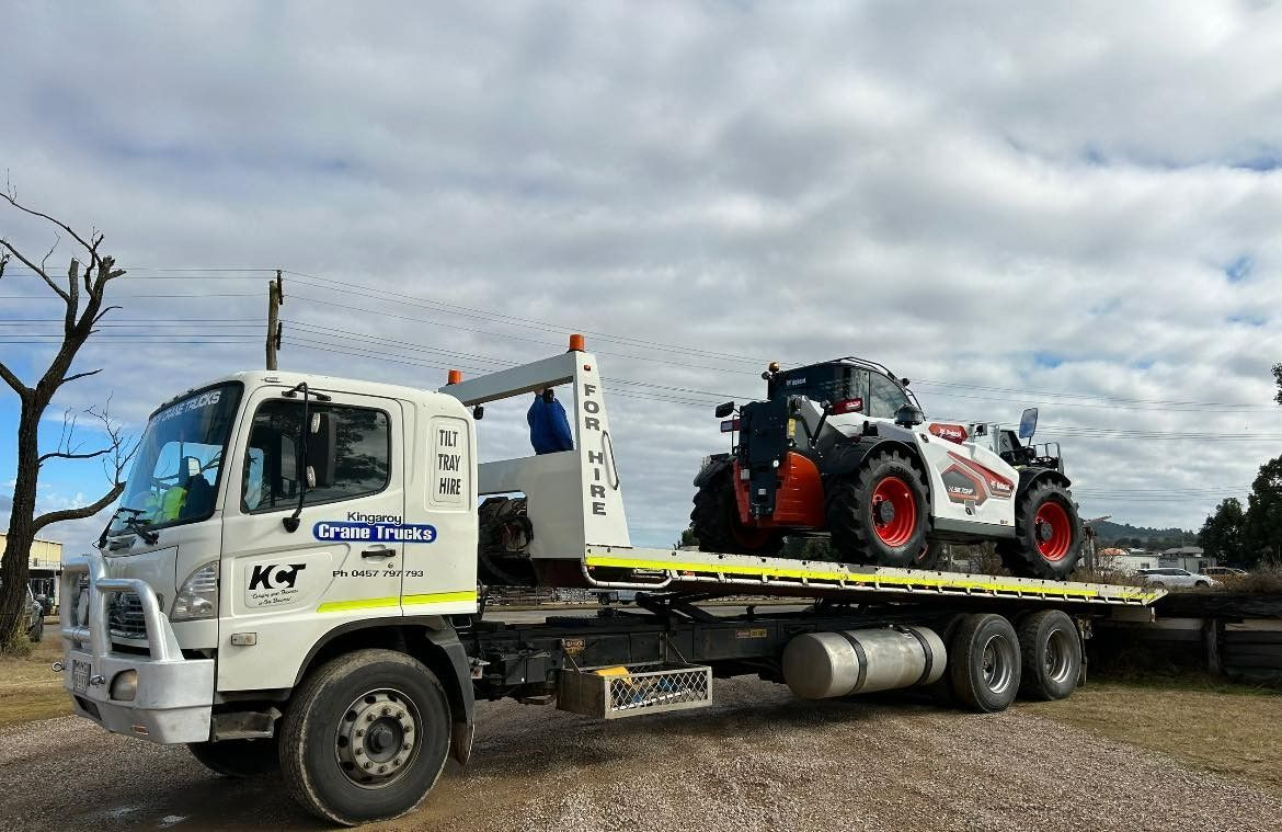 A Tow Truck With Two Tractors On The Back Is Parked — Kingaroy Crane Trucks & Equipment Hire In Kingaroy, QLD