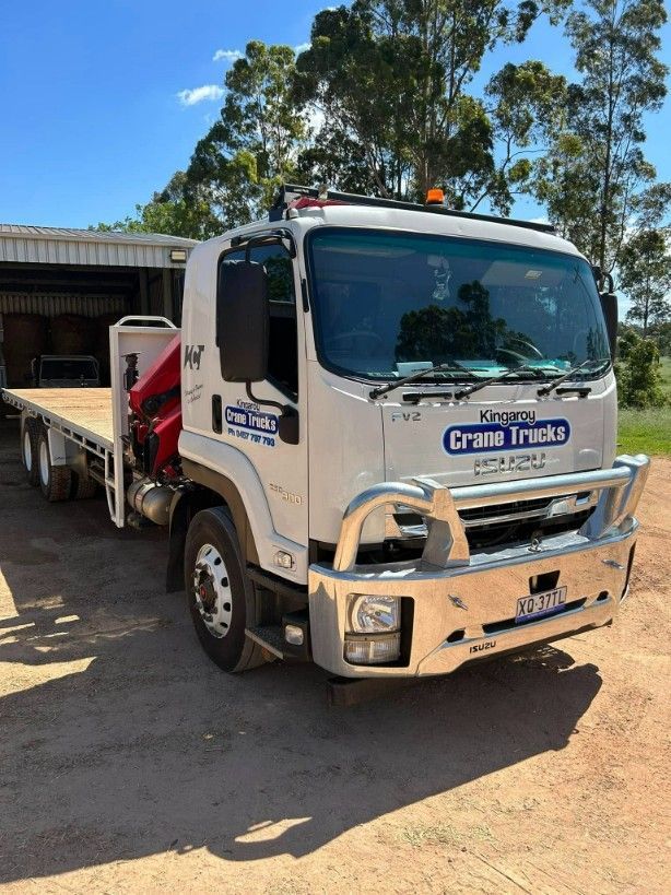 A White Truck With A Flat Bed Is Parked In The Dirt — Kingaroy Crane Trucks & Equipment Hire In Cooyar, QLD