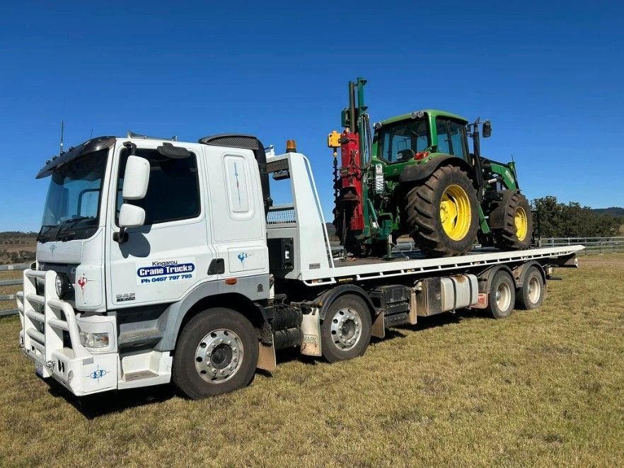A White Tow Truck Is Carrying A Green Tractor — Kingaroy Crane Trucks & Equipment Hire In Kingaroy, QLD