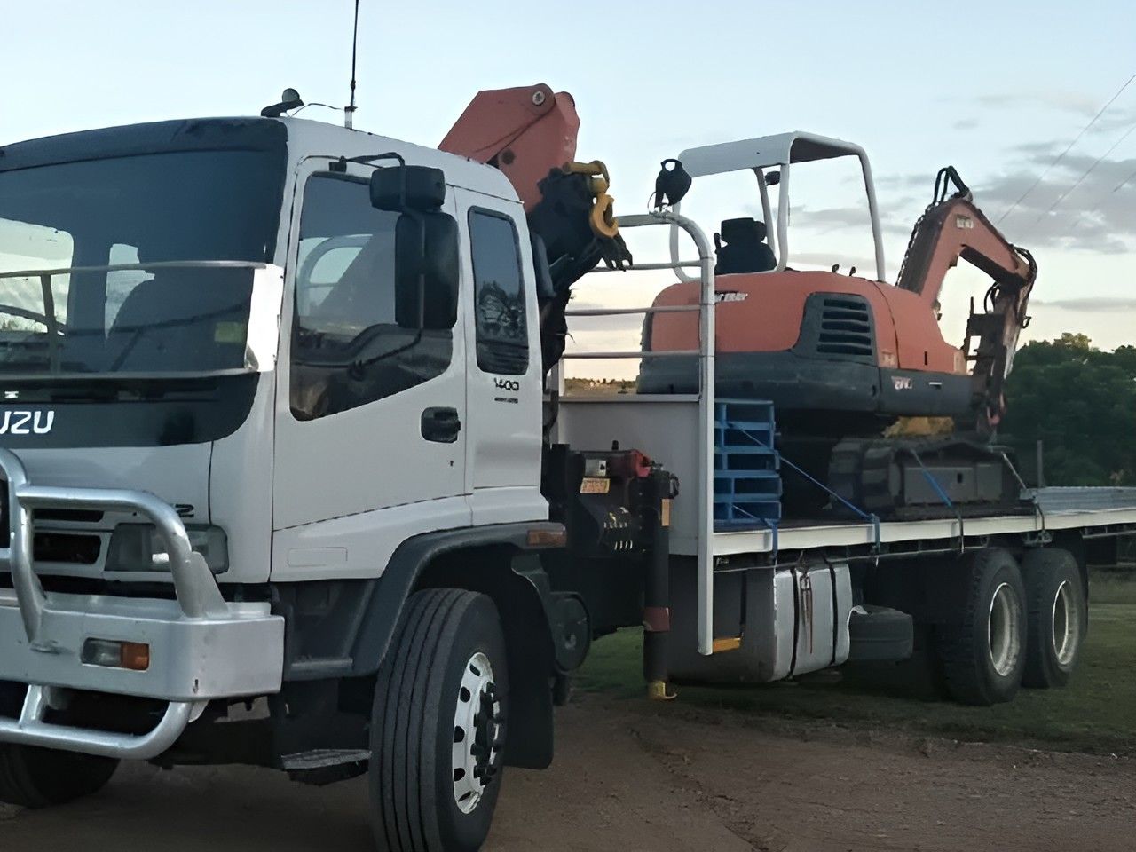 A White Truck With An Excavator On The Back Of It — Kingaroy Crane Trucks & Equipment Hire In Nanango, QLD