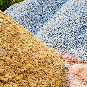 Piles of sand, gravel, and crushed stone in tan, blue-gray, and pink hues
