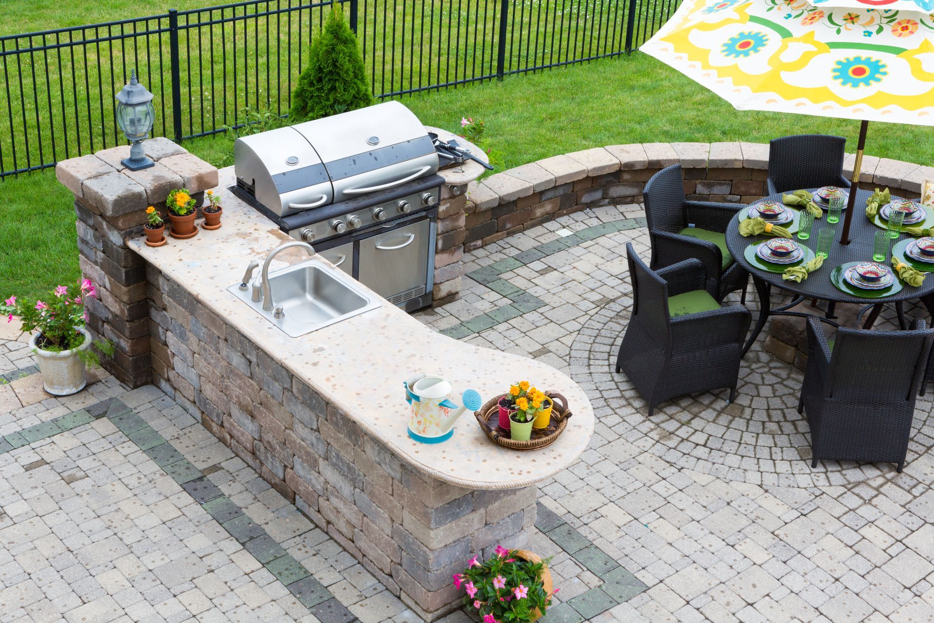 Outdoor patio with built-in grill, stone bar, and round dining table with chairs and place settings