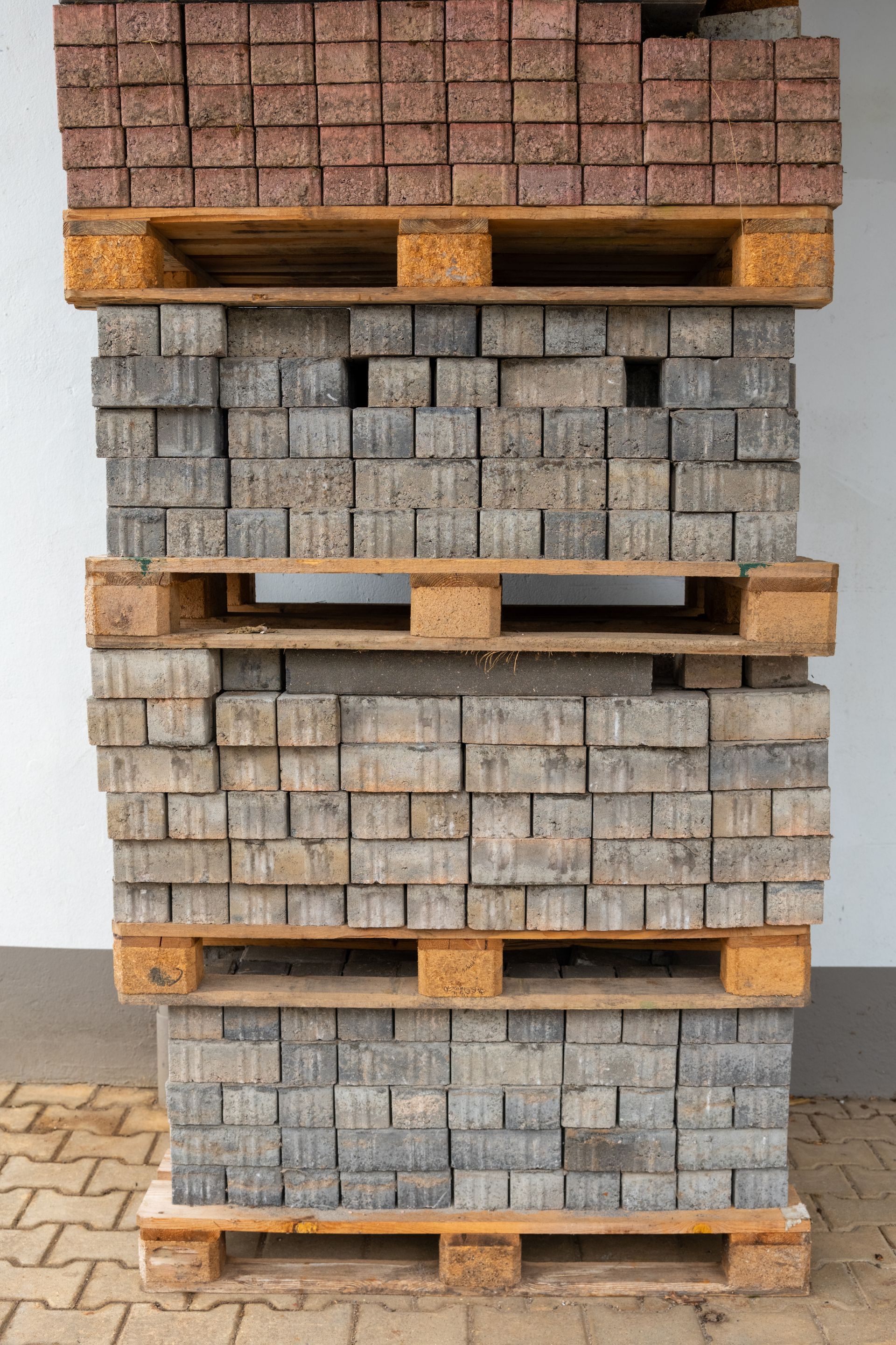 Stacked wooden pallets holding gray concrete pavers indoors