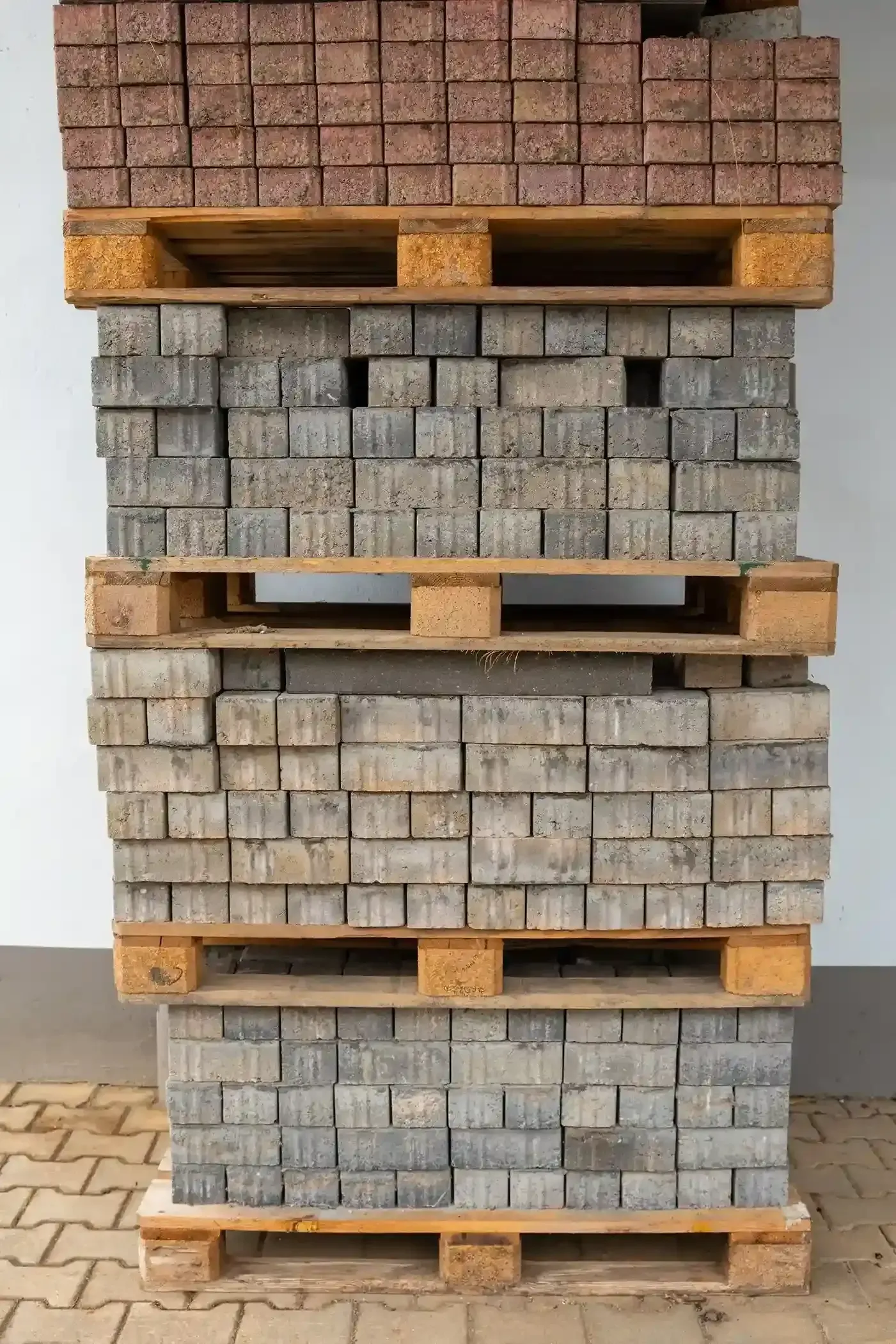 Stacked wooden pallets holding gray concrete pavers indoors