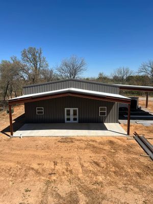 Gray metal building with brown trim and white doors, under a clear blue sky.
