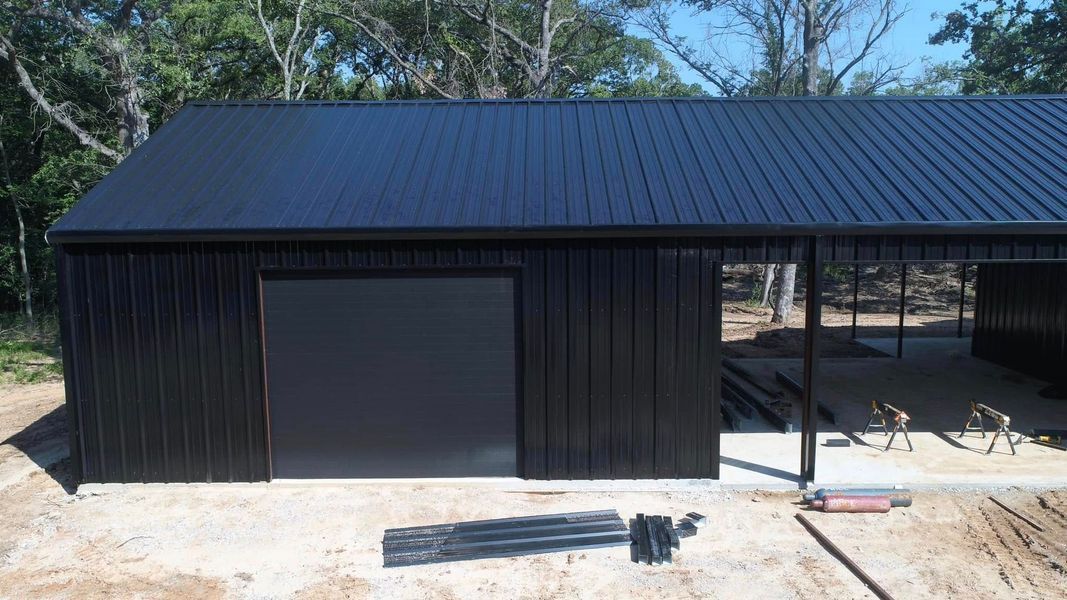 Black metal shed with matching roof and a covered open side.
