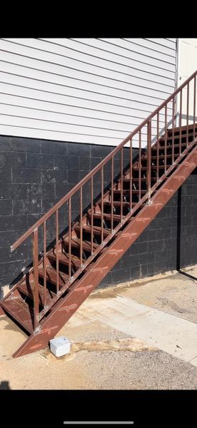 Brown metal staircase against a white and black building exterior.