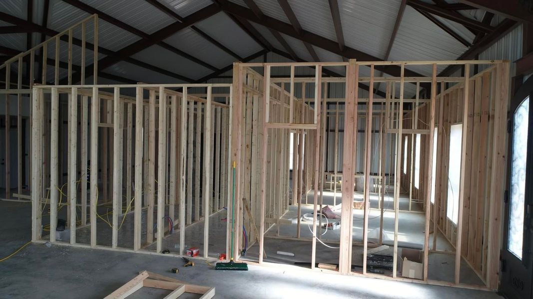 Interior of a building under construction, wooden wall framing visible.
