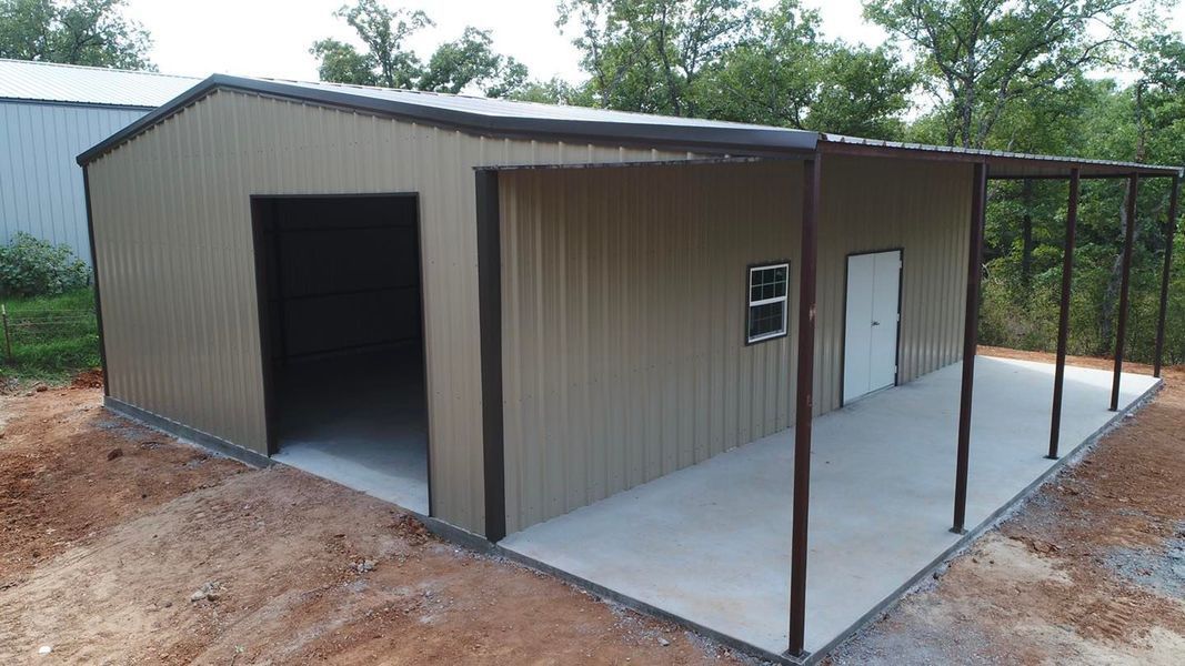 Tan metal building with open garage, small window, white door, and covered porch on a concrete slab.