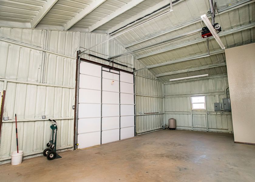 Interior of a garage with white walls and a large closed garage door. Empty concrete floor.
