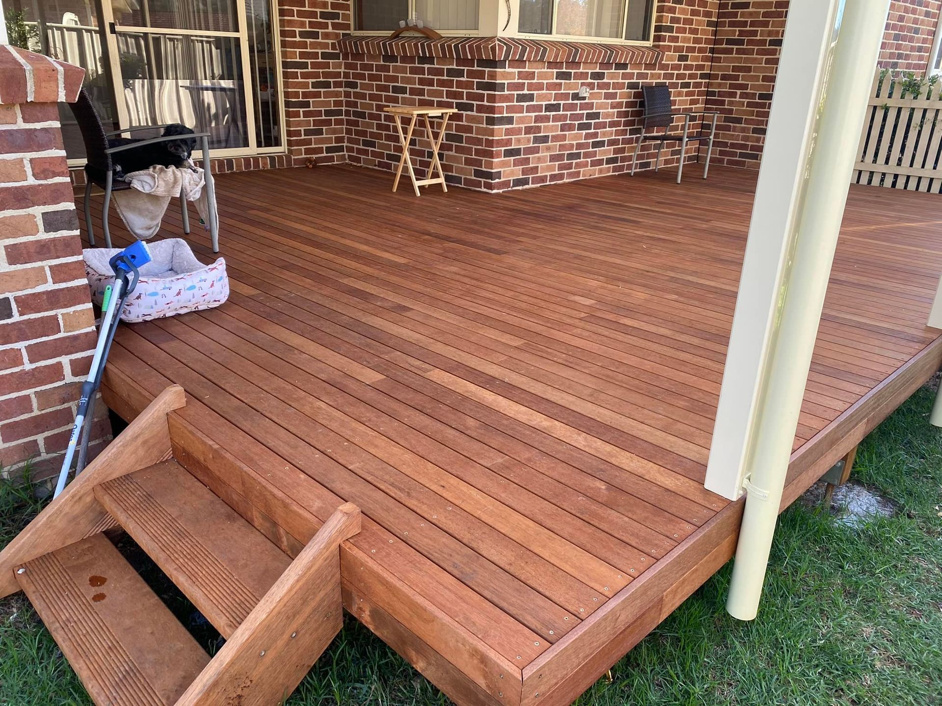 A white patio cover is being installed on the side of a brick house.
