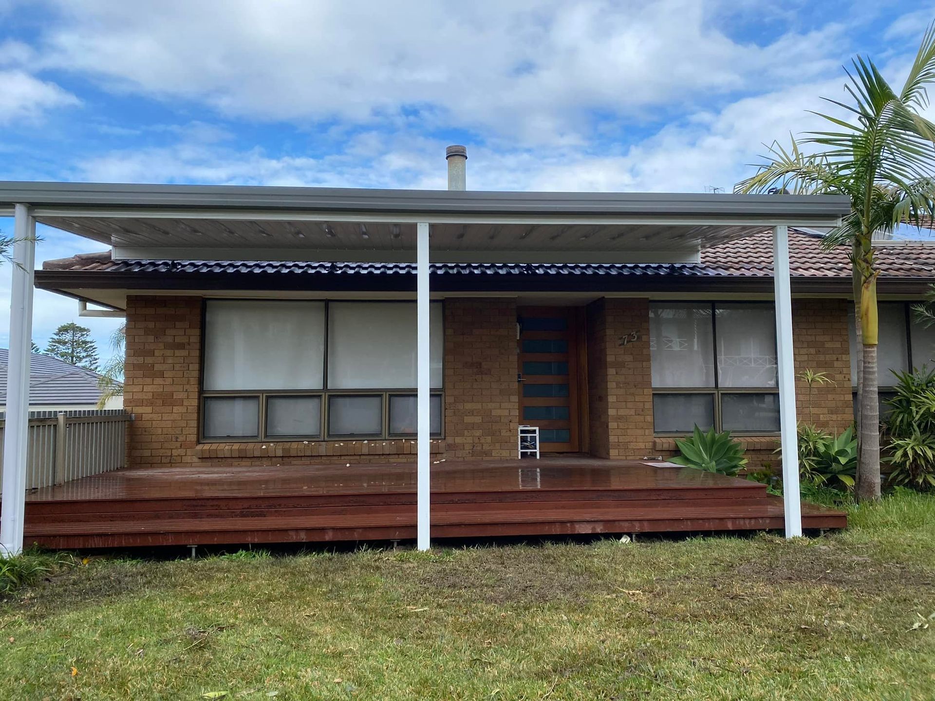A brick house with a wooden deck and a covered porch