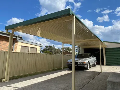 A white patio cover is being installed on the side of a brick house.