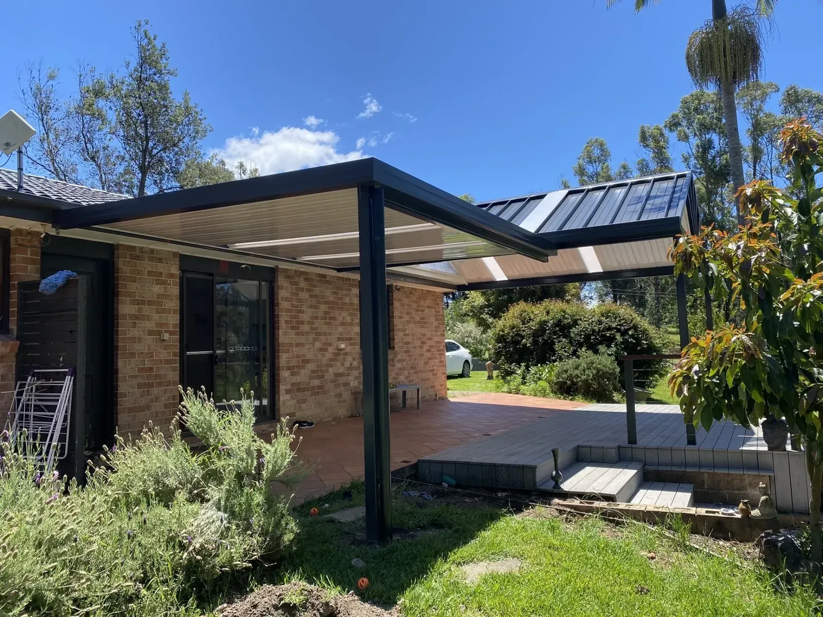 A white patio cover is being installed on the side of a brick house.
