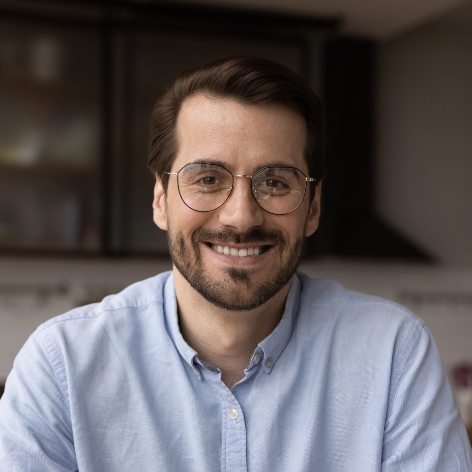 A man with glasses and a beard is smiling for the camera.