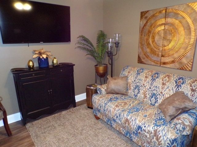 Living room with floral sofa, wall-mounted TV, black cabinet, and decorative wall art