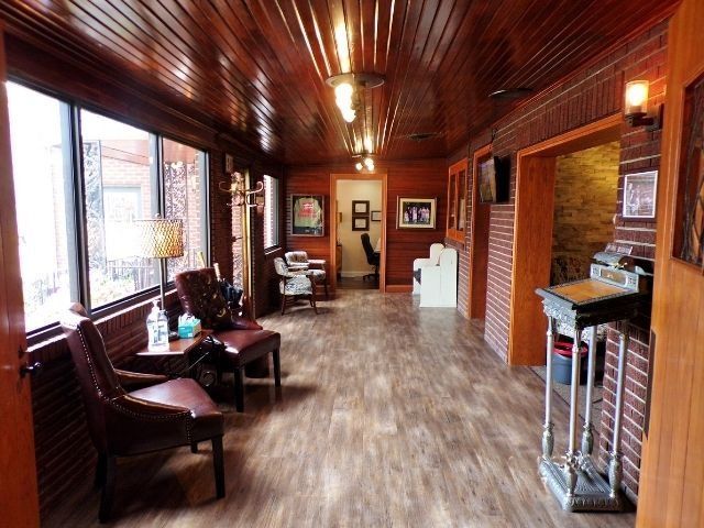 Wood-paneled hallway with chairs, framed art, and a reception counter at the end