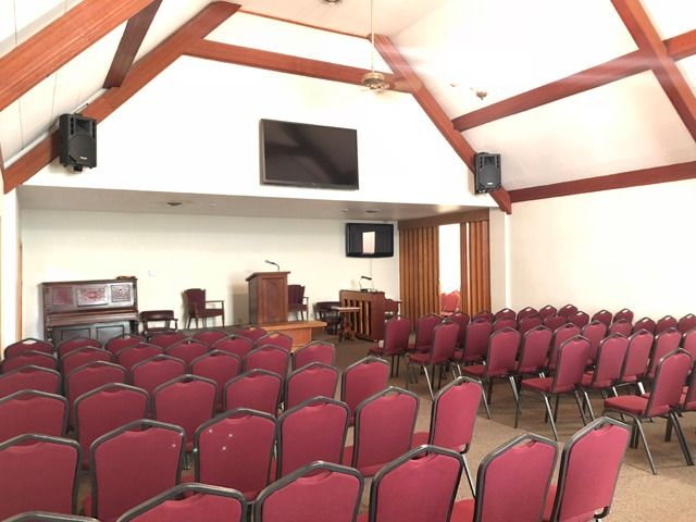 Empty church sanctuary with rows of red chairs facing a stage and large screen