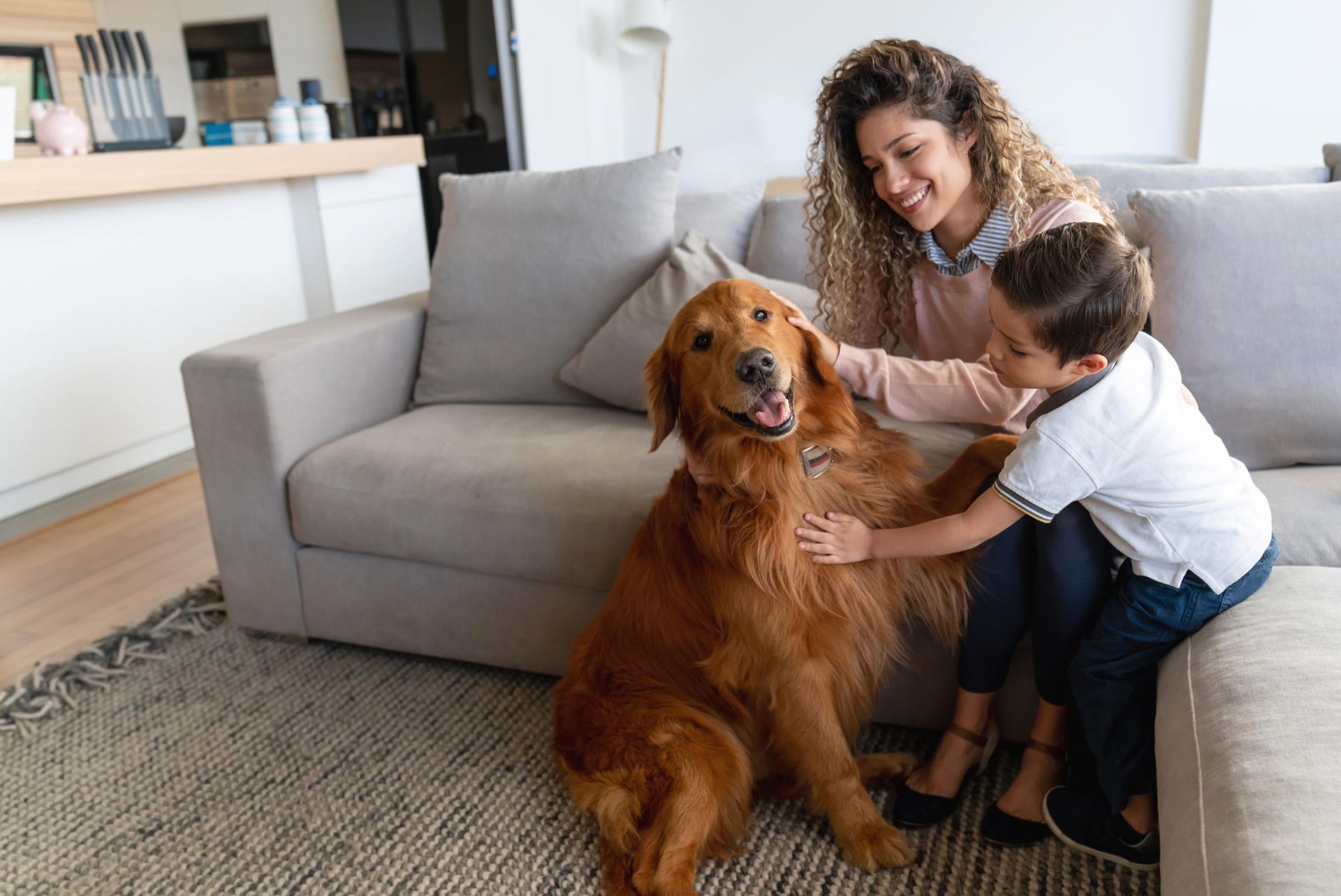 A woman and a child are petting a dog on a couch.