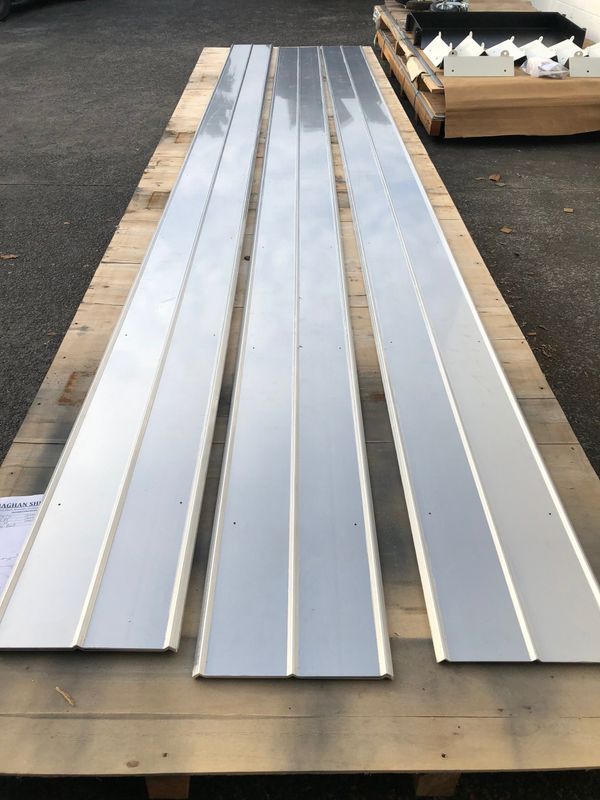 Three pieces of metal are sitting on a wooden pallet.