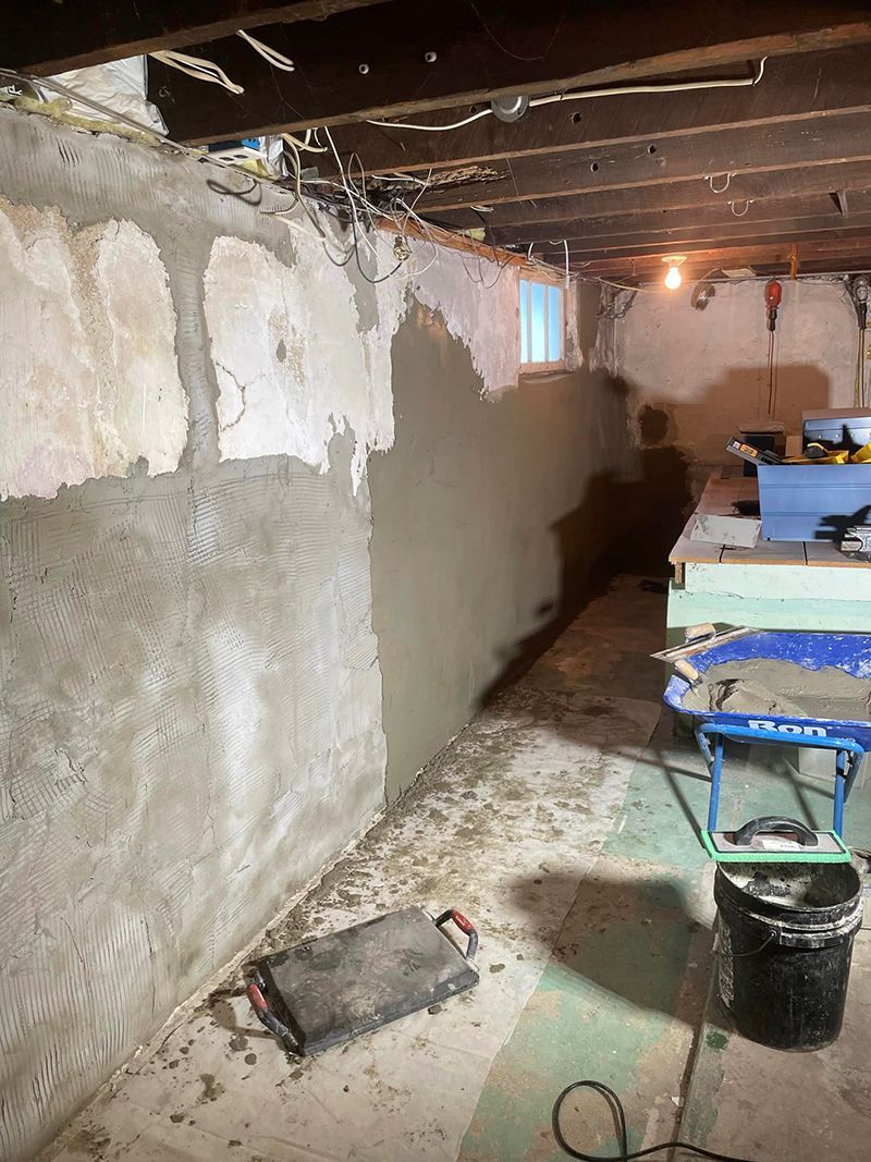 Basement wall with fresh concrete patch and construction debris.