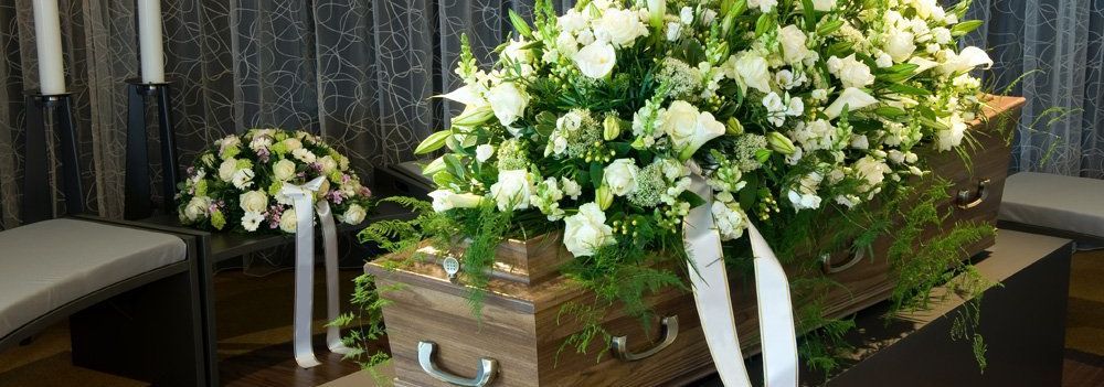 coffin with white flower tribute on top