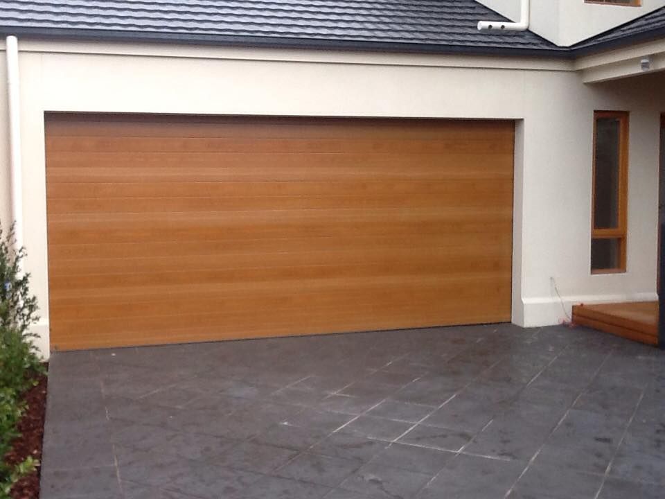 A Wooden Garage Door Sits In Front Of A White House – East Gippsland, VIC - East Gippsland Garage Doors & Maintenance